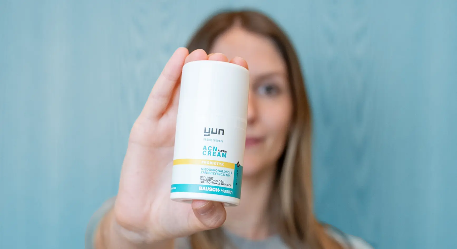 Kobieta trzymająca w ręce przed sobą opakowanie kremu Yun ACN Repair Cream